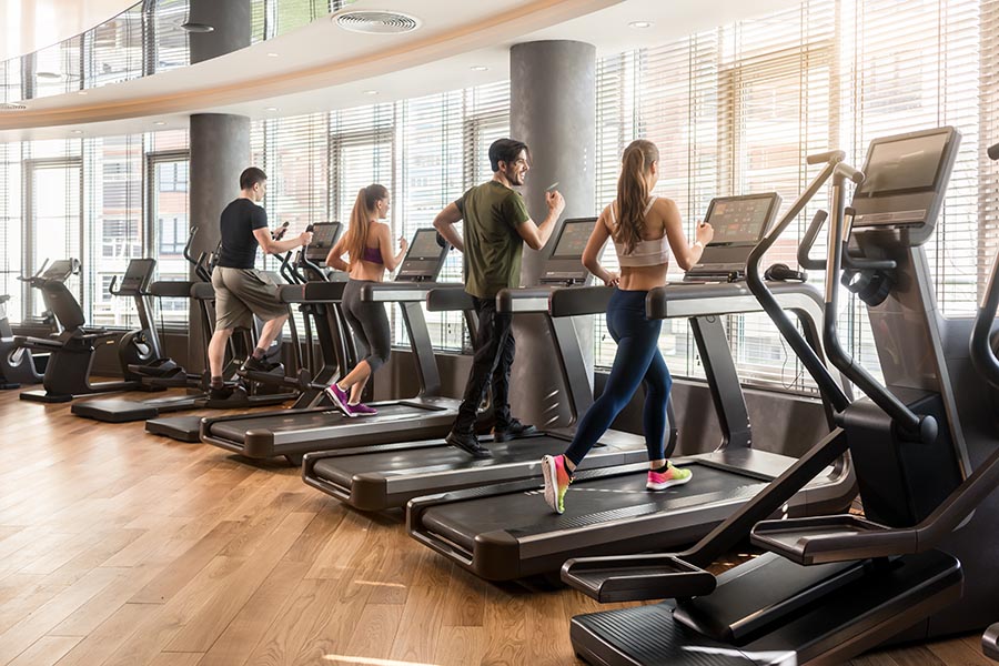 Specialized Business Insurance - Fitness Center With Several Members Running on Treadmills Facing a Large Curved Wall of Windows
